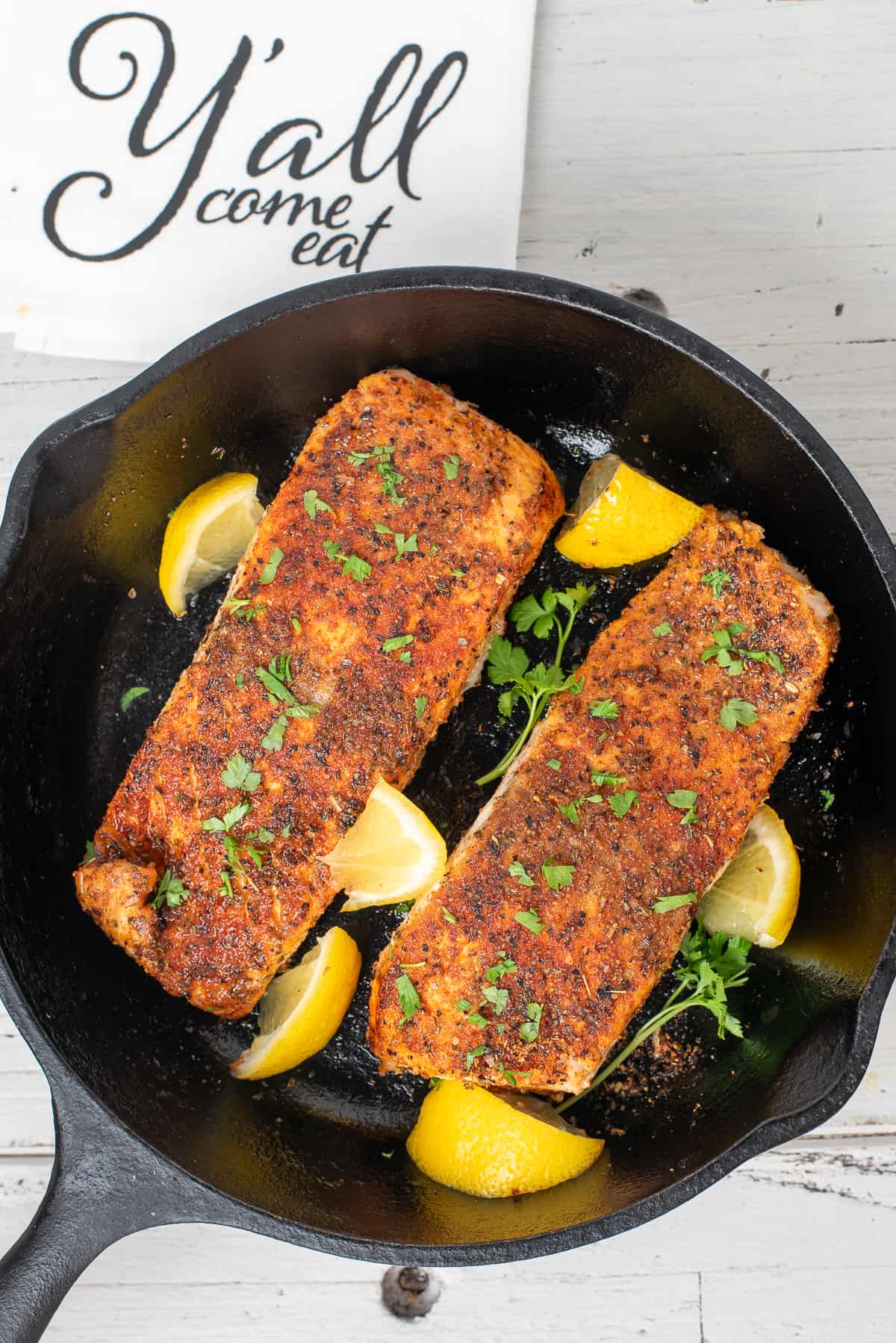 blackened baked salmon in iron skillet with lemon.