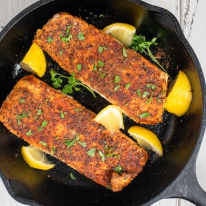 blackened baked salmon with lemon in skillet.