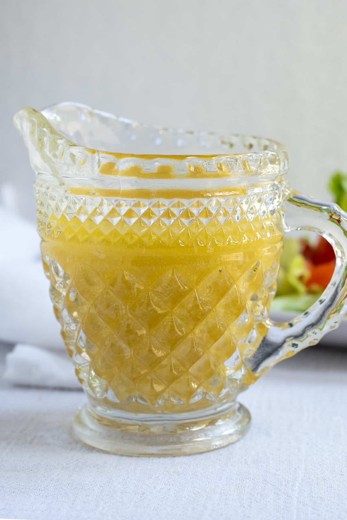 citrus salad dressing in glass pitcher on white background