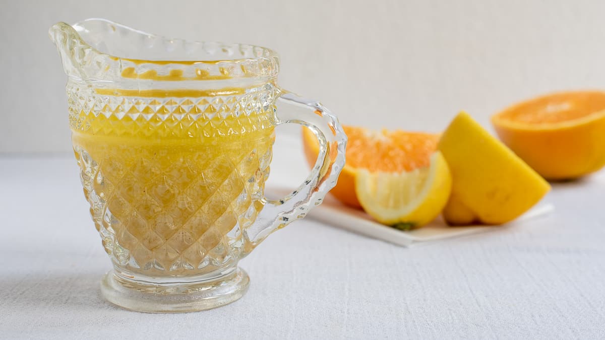 citrus salad dressing in glass pitcher with oranges in background