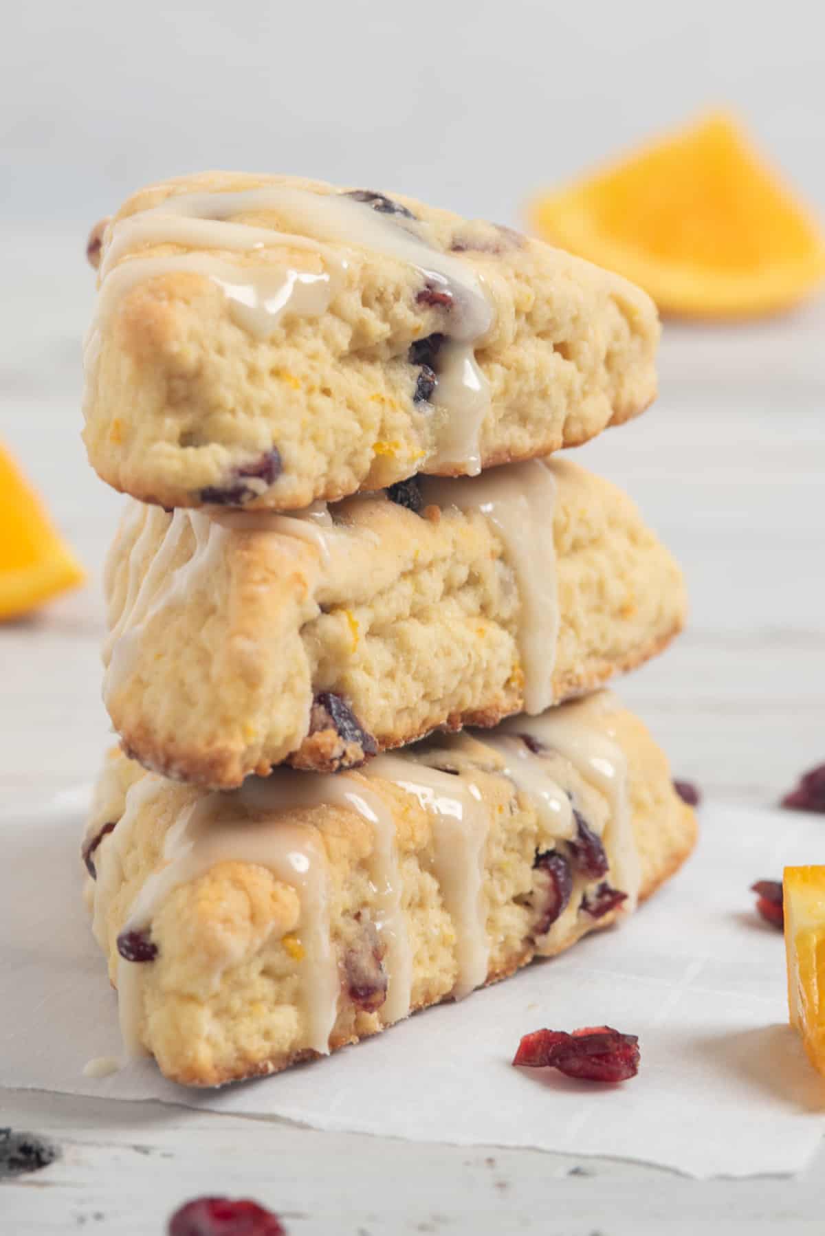 3 scones stacked up with cranberries and orange pieces around. 