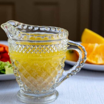 citrus salad dressing in glass pitcher with oranges in background