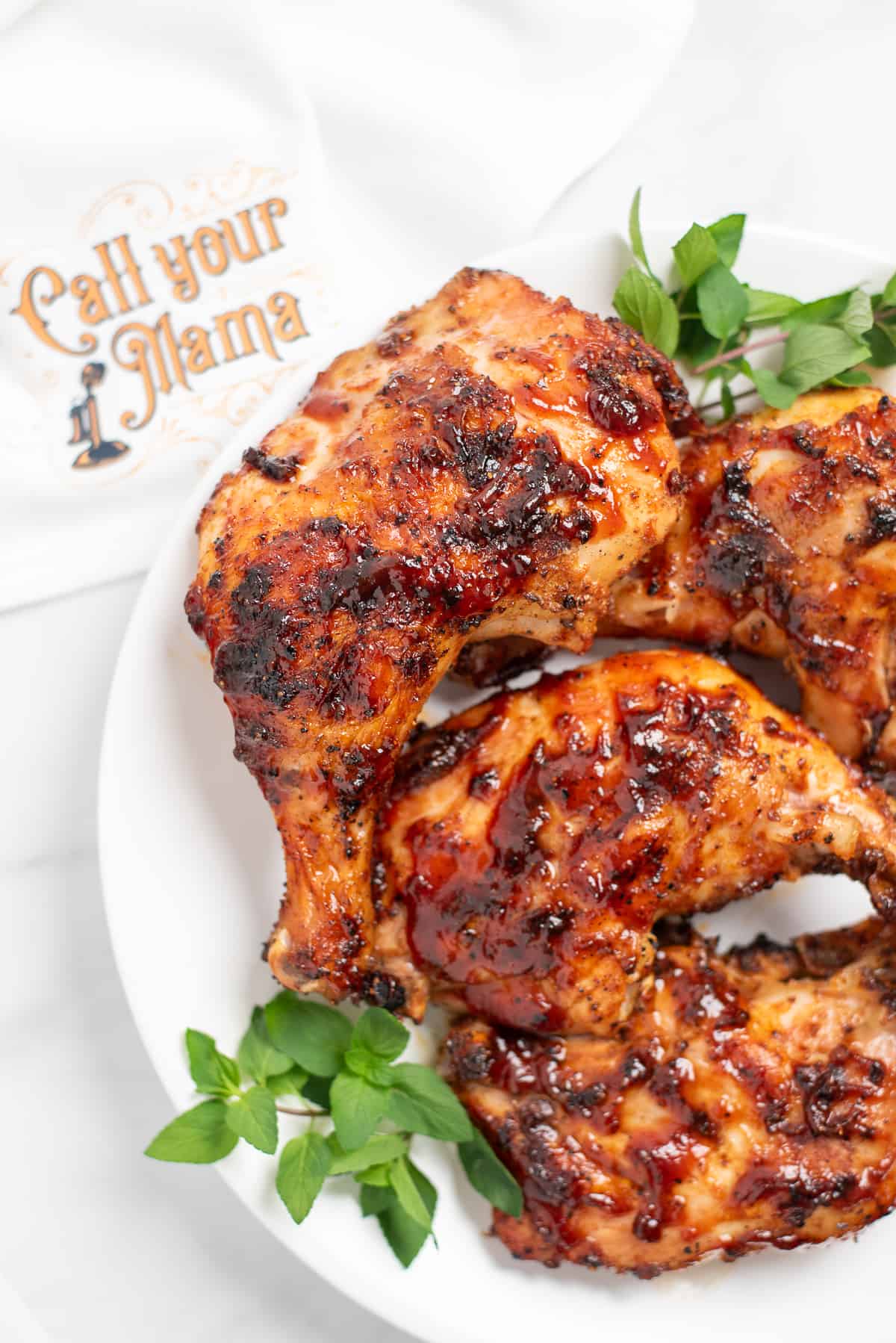 bbq chicken quarters on plate with greenery.