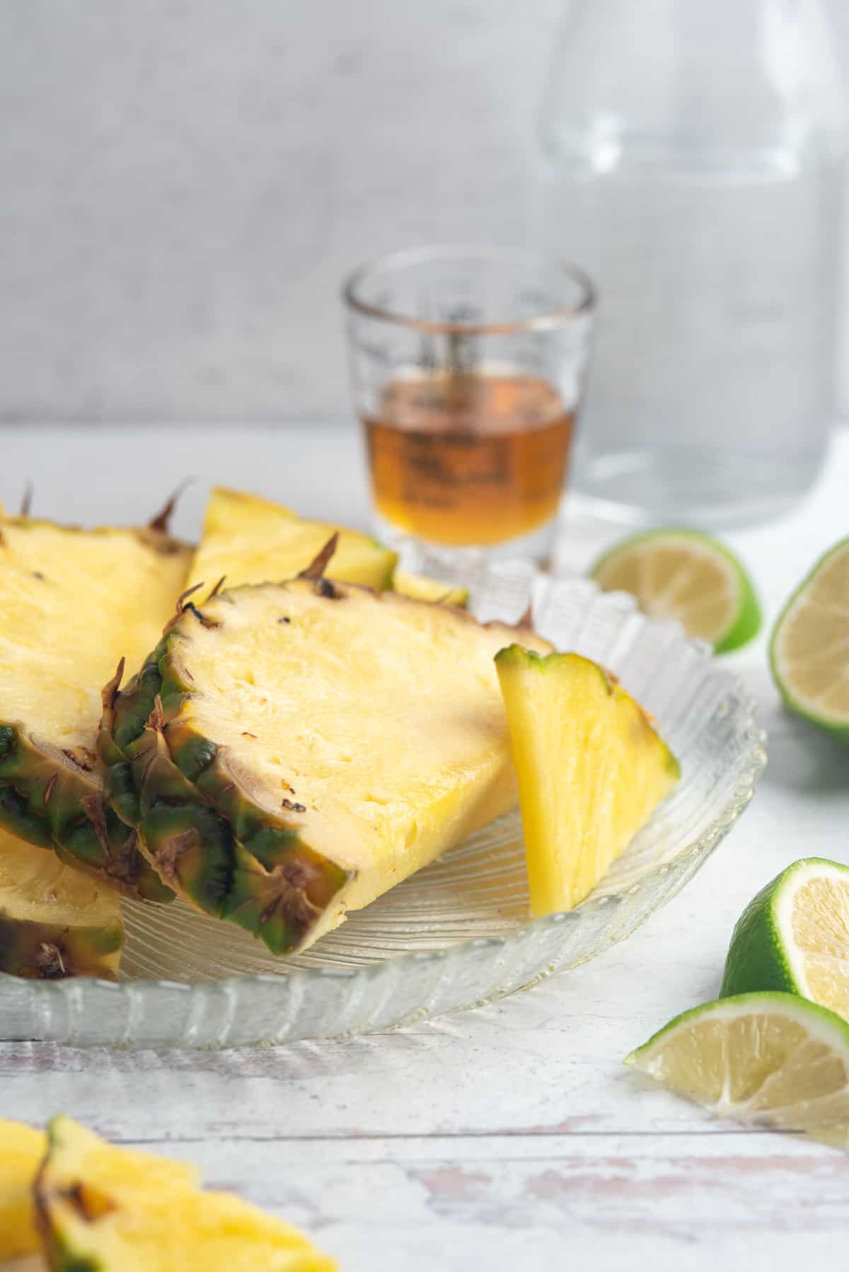 Ingredients for pineapple agua fresca including fresh pineapple, lime, and honey in glass containers on a white background