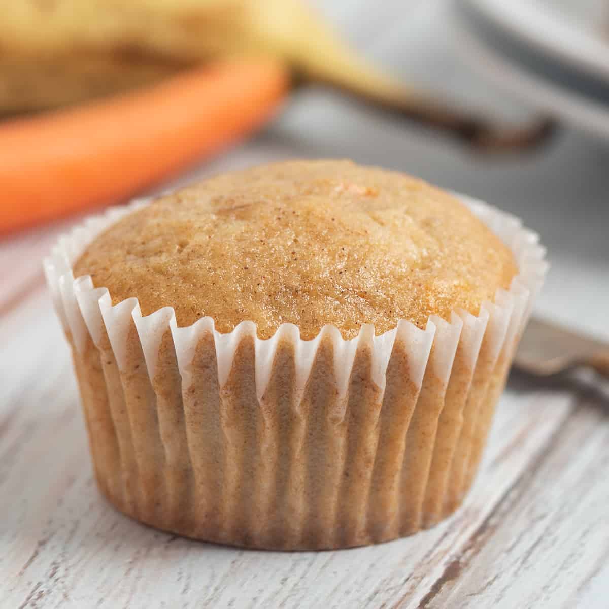 banana carrot muffin with carrot and banana behind.