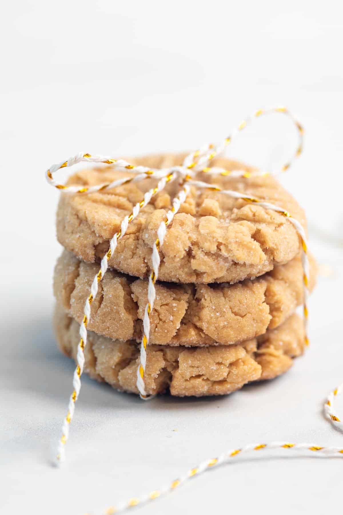 stacked chewy peanut butter cookies tied up with a white and gold string