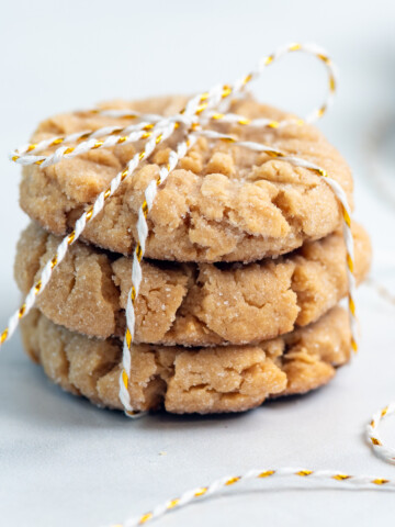 chewy peanut butter cookies tied up with white and red string on a white background