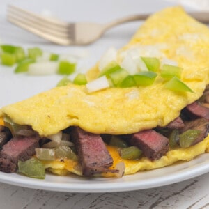 steak omelet on a white plate with fork in background