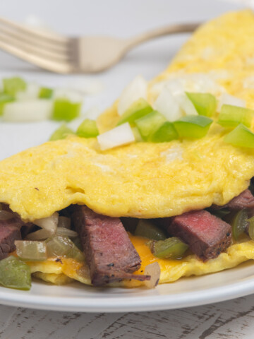 steak omelet on a white plate with fork in background