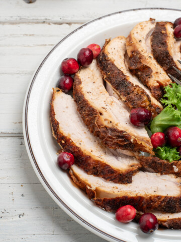 sliced cajun fried turkey breast on a white plate with a white background