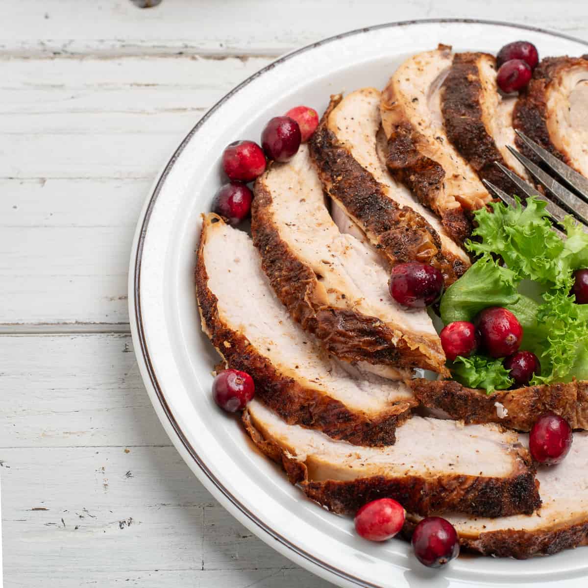 sliced cajun fried turkey breast on a white plate with a white background