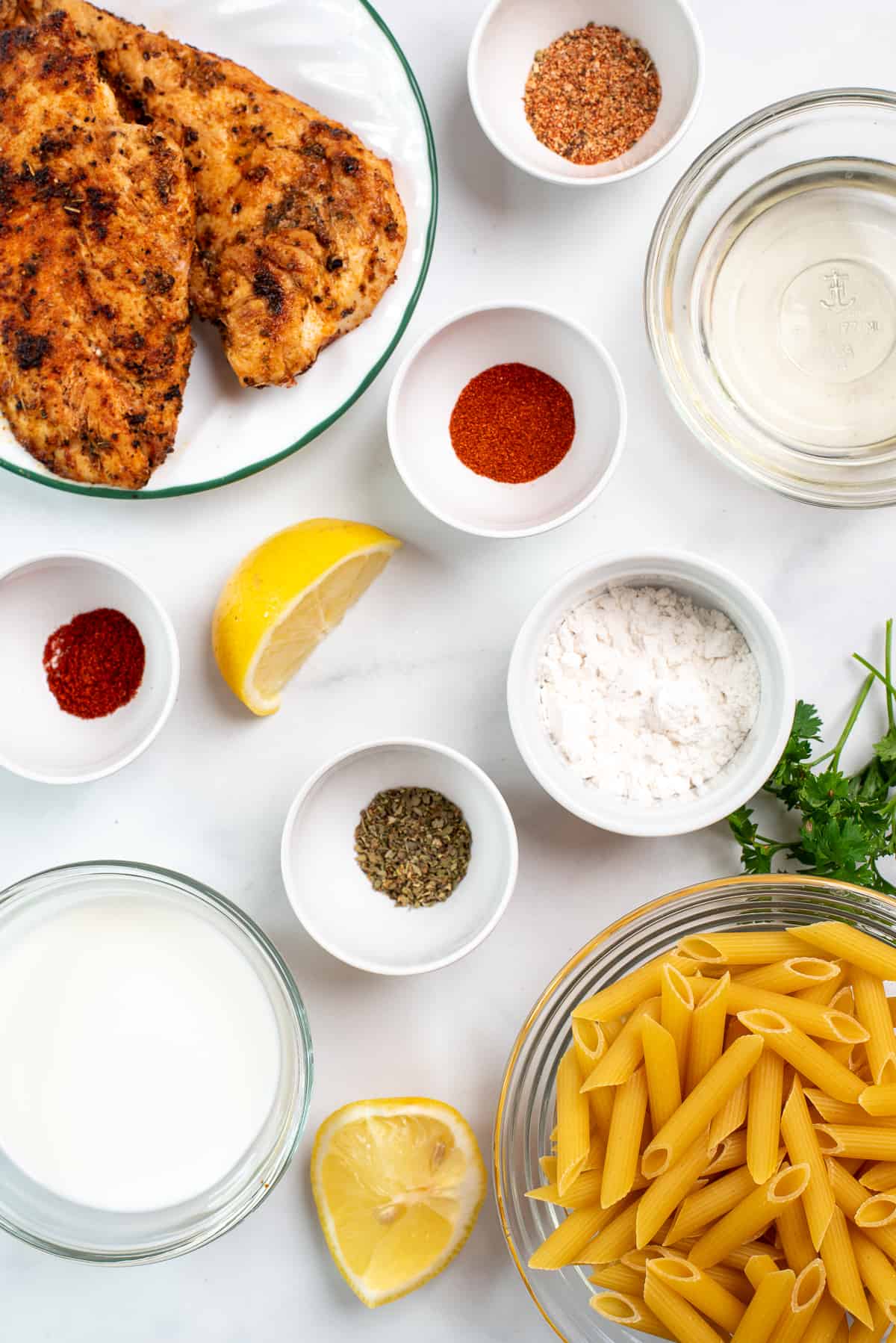 ingredients needed for spicy chicken pasta on a white background.
