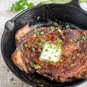 blackened ribeye steak with butter in skillet.