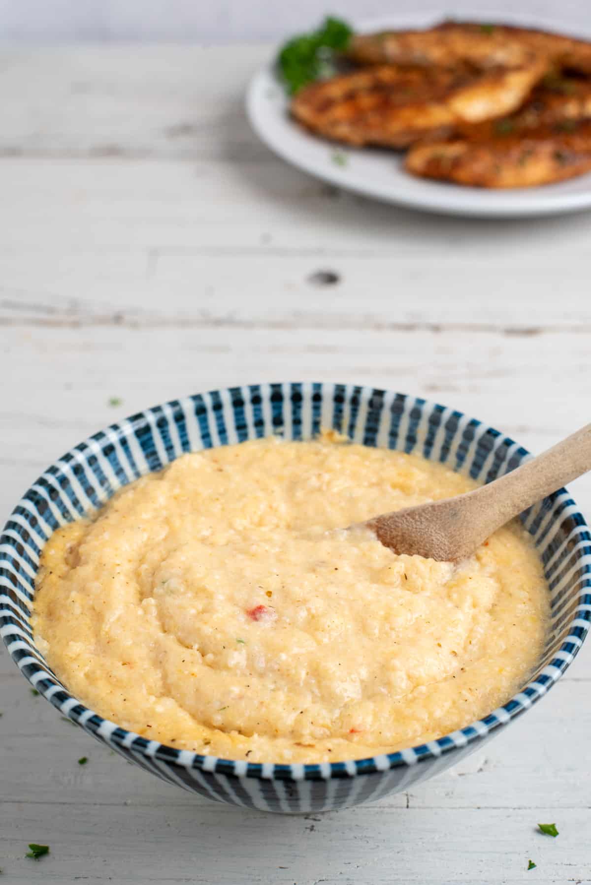 striped bowl with pimento cheese grits and spoon.