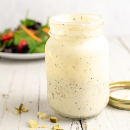 ranch in a mason jar with dill pickles scattered around