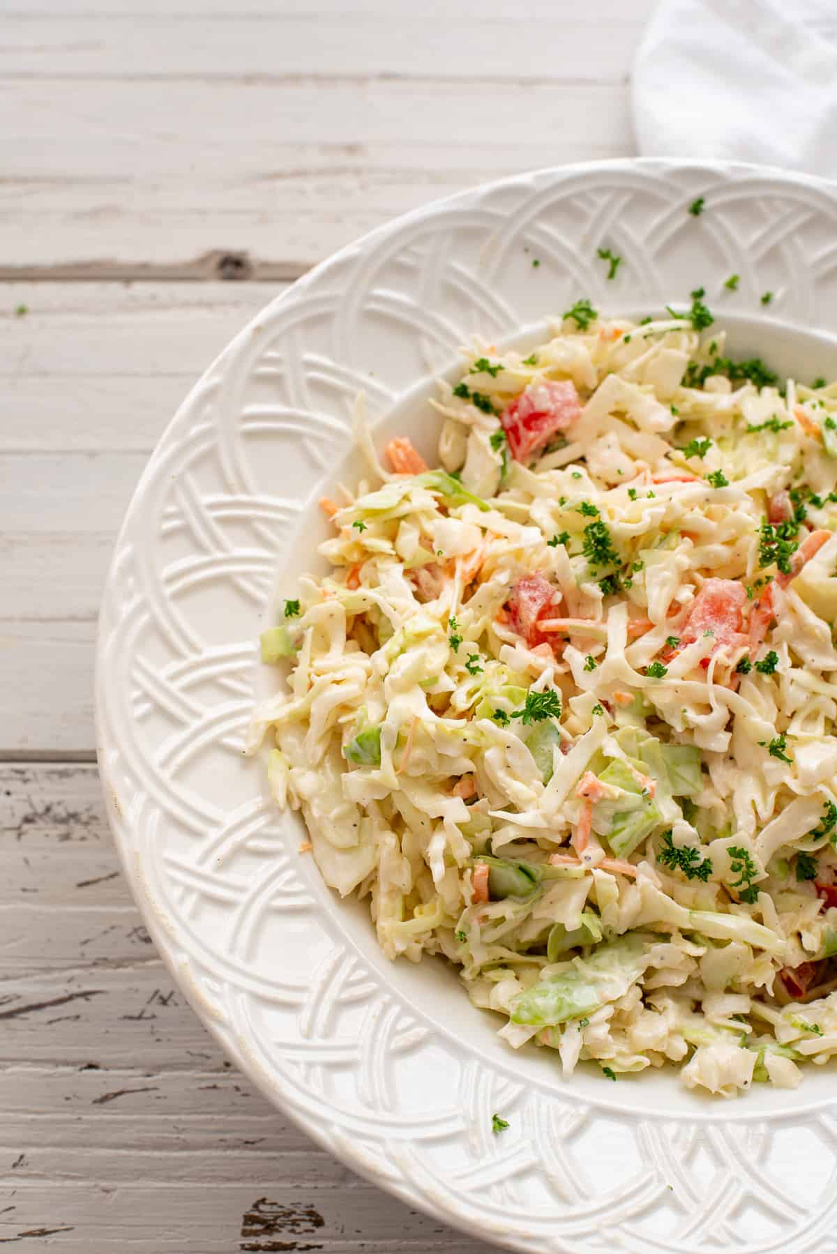 off center photo of summer slaw in white bowl. 