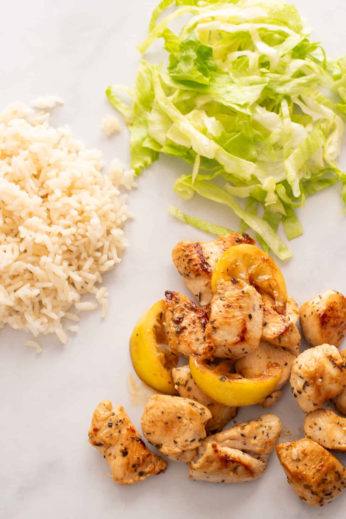 Greek lemon chicken, rice, and lettuce on a white background.