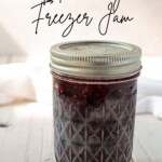 A mason jar of blackberry freezer jam with the recipe title in a text overlay.