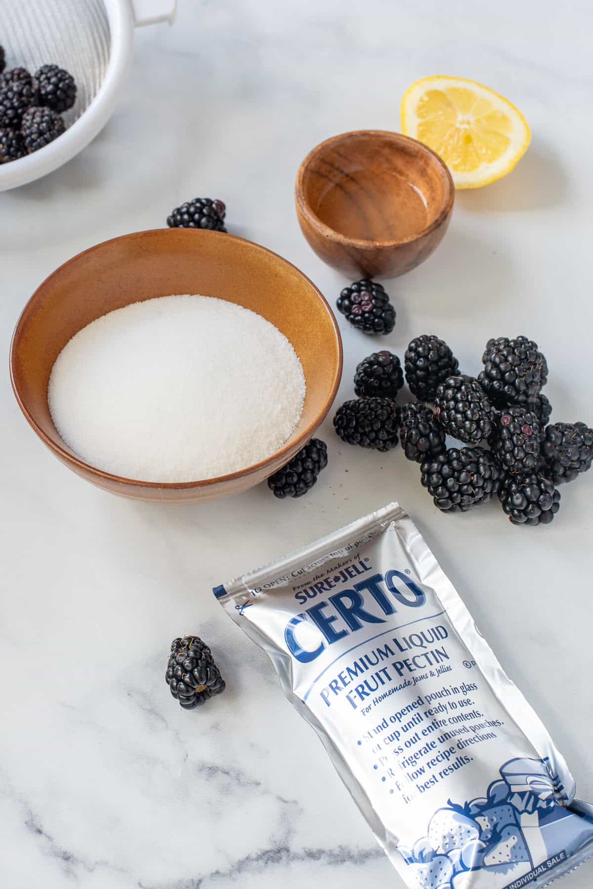 The ingredients needed to make blackberry freezer jam on a white background.