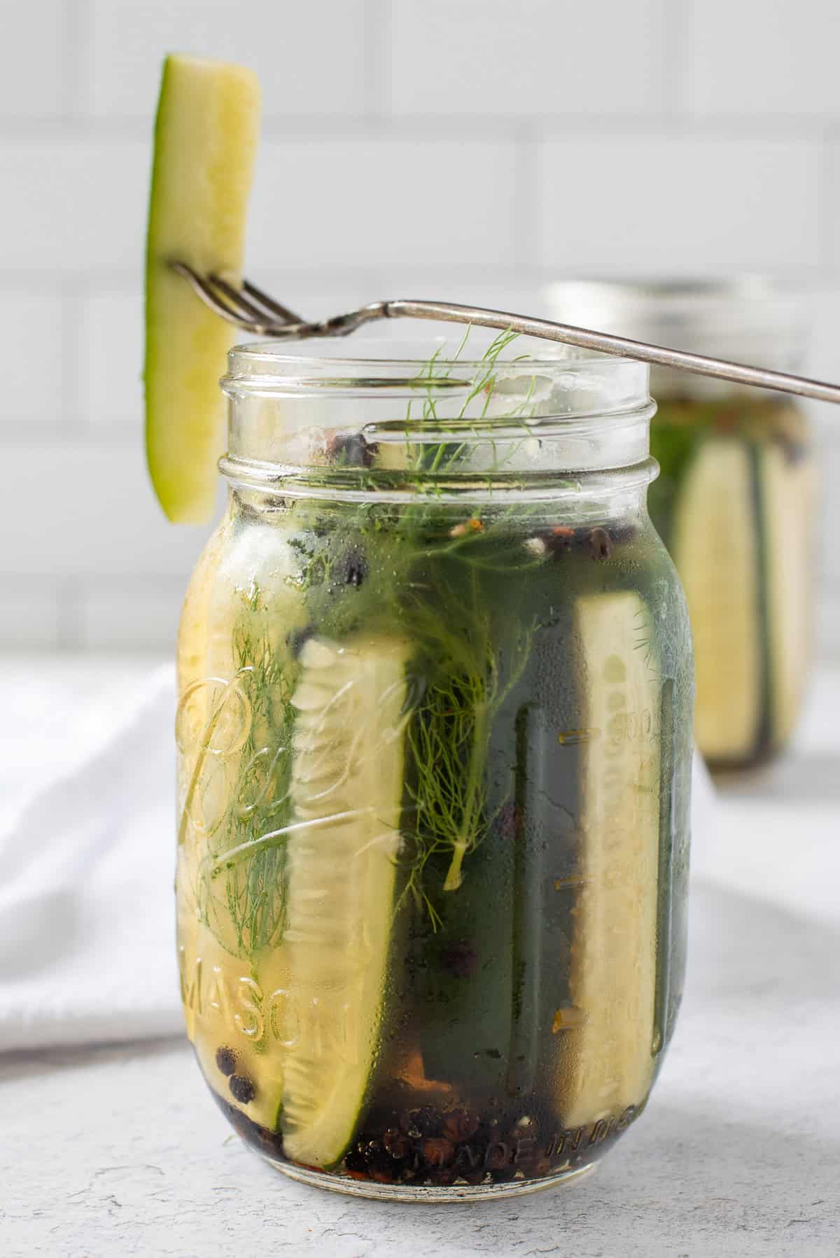 close up of jar of refrigerator pickles with fork.