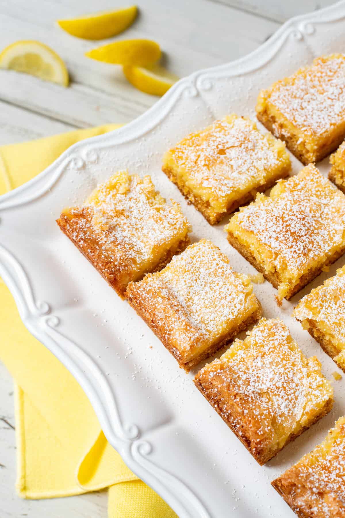 gooey lemon butter cake squares on white plate.