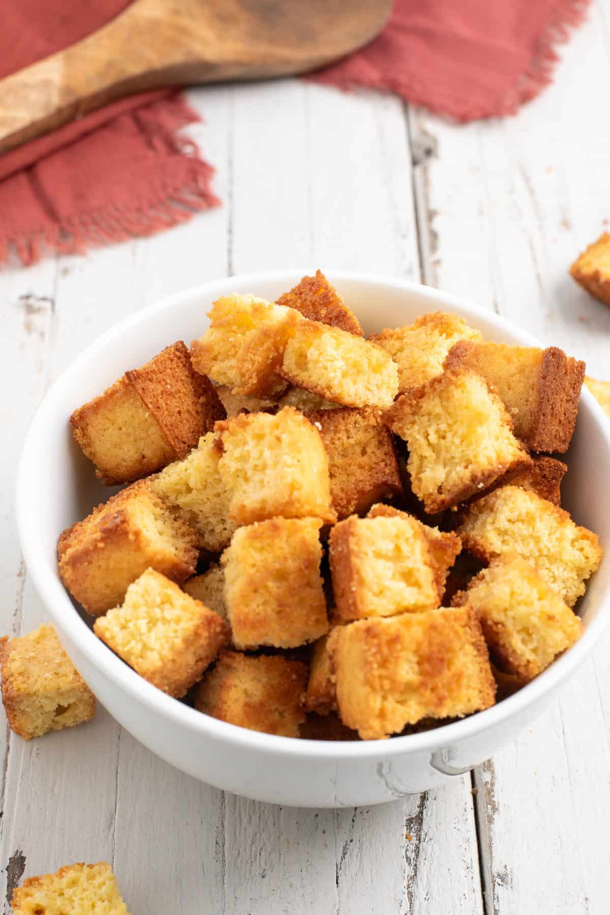 a white bowl of croutons on a white wooden table