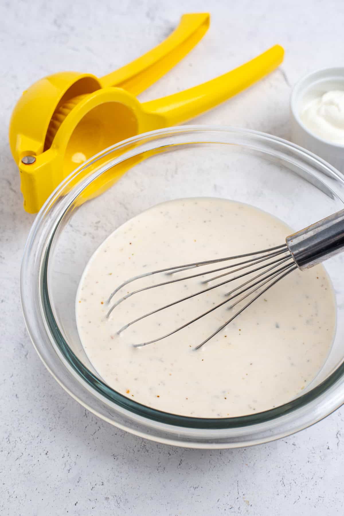 bowl with greek dressing and whisk.