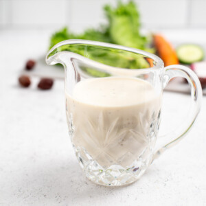 square image of glass pitcher with greek salad dressing.