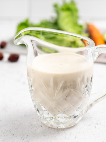 square image of glass pitcher with greek salad dressing.