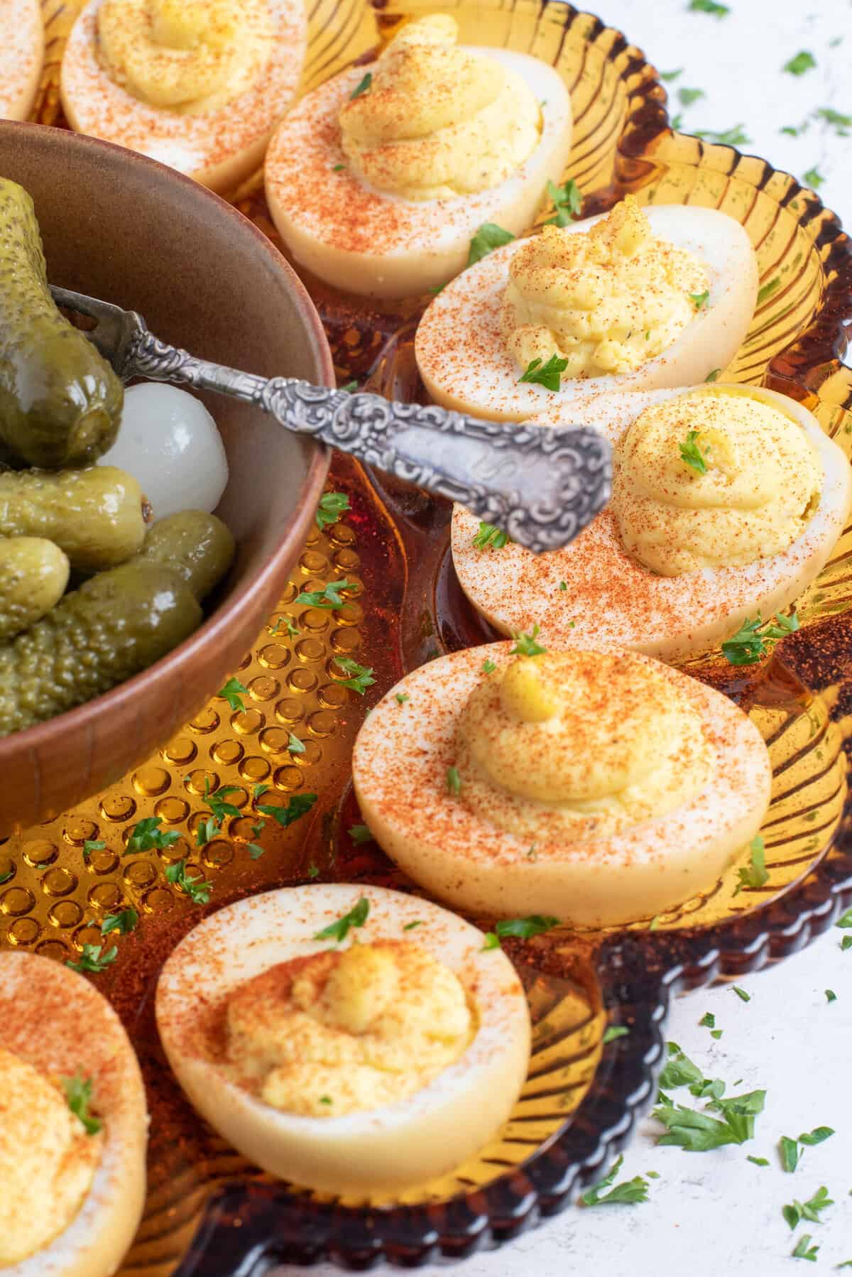 smoked deviled eggs on platter with pickles.