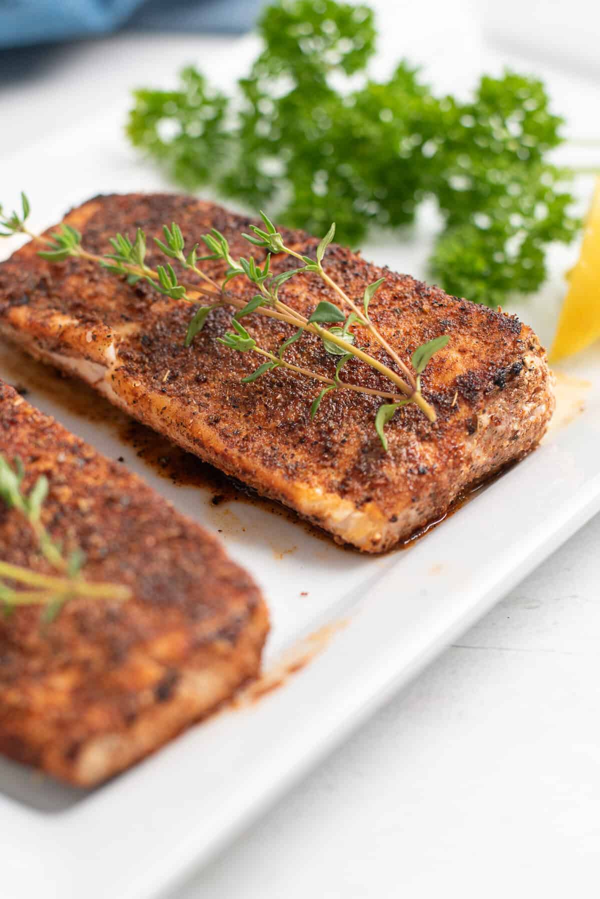 blackened grouper on white platter with herbs.