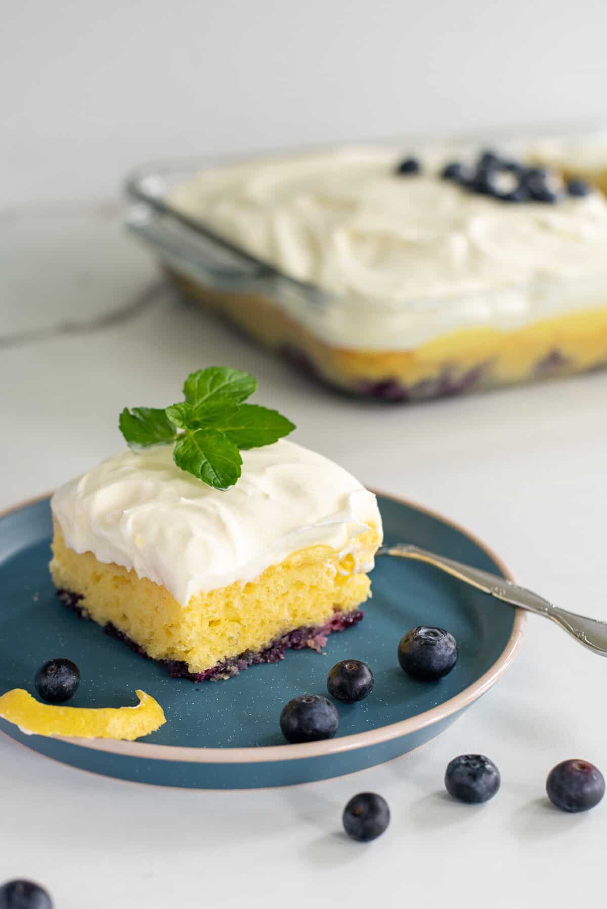 lemon blueberry poke cake on a blue plate