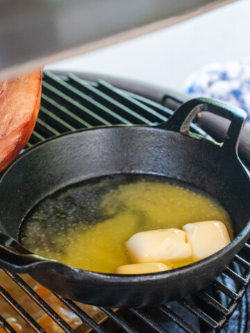 square image of butter smoking on grill.