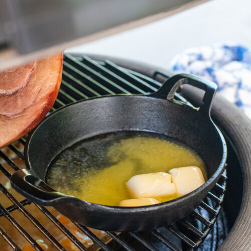 square image of butter smoking on grill.