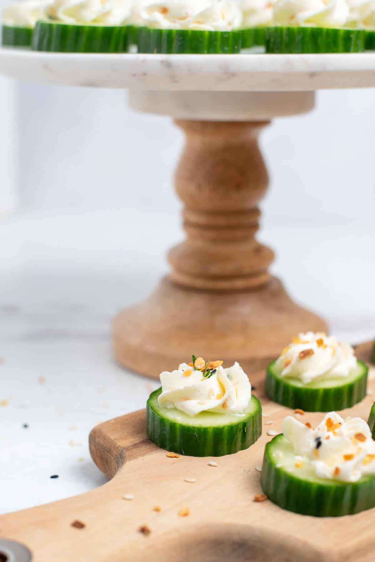 close up of cream cheese cucumber bites with stand behind.