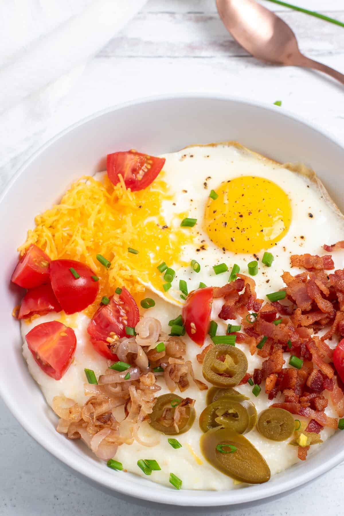 overhead shot of cheesy grits bowl with toppings. 