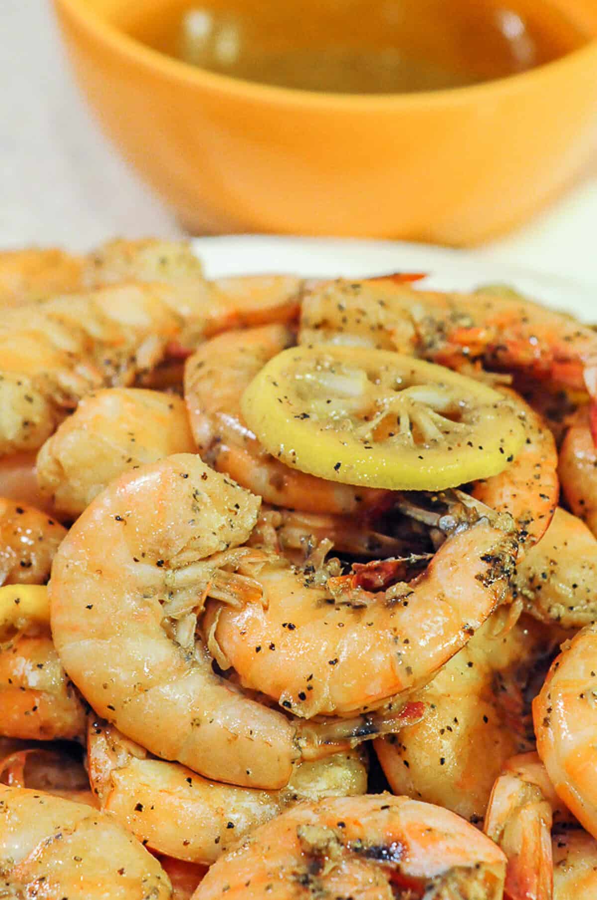 fiery cajun shrimp with bowl of sauce behind. 