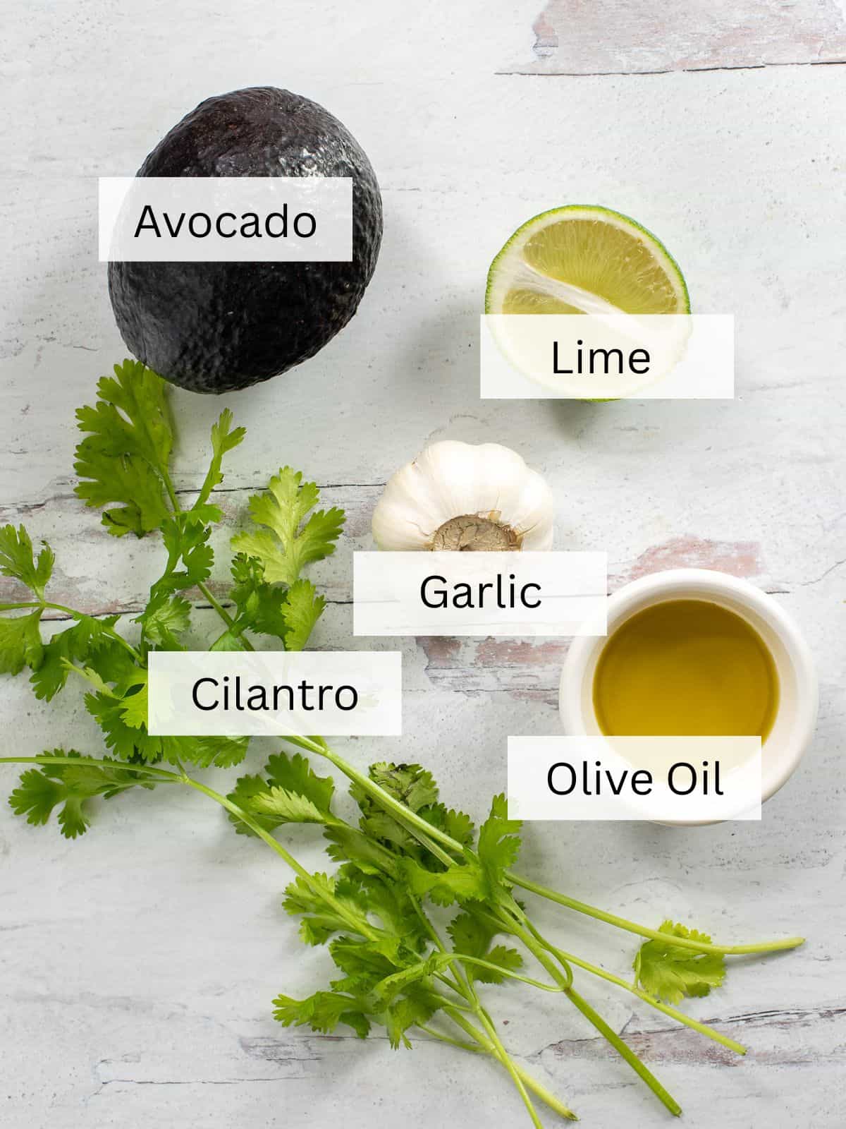 The ingredients needed for making Avocado Lime Dressing on a white countertop.