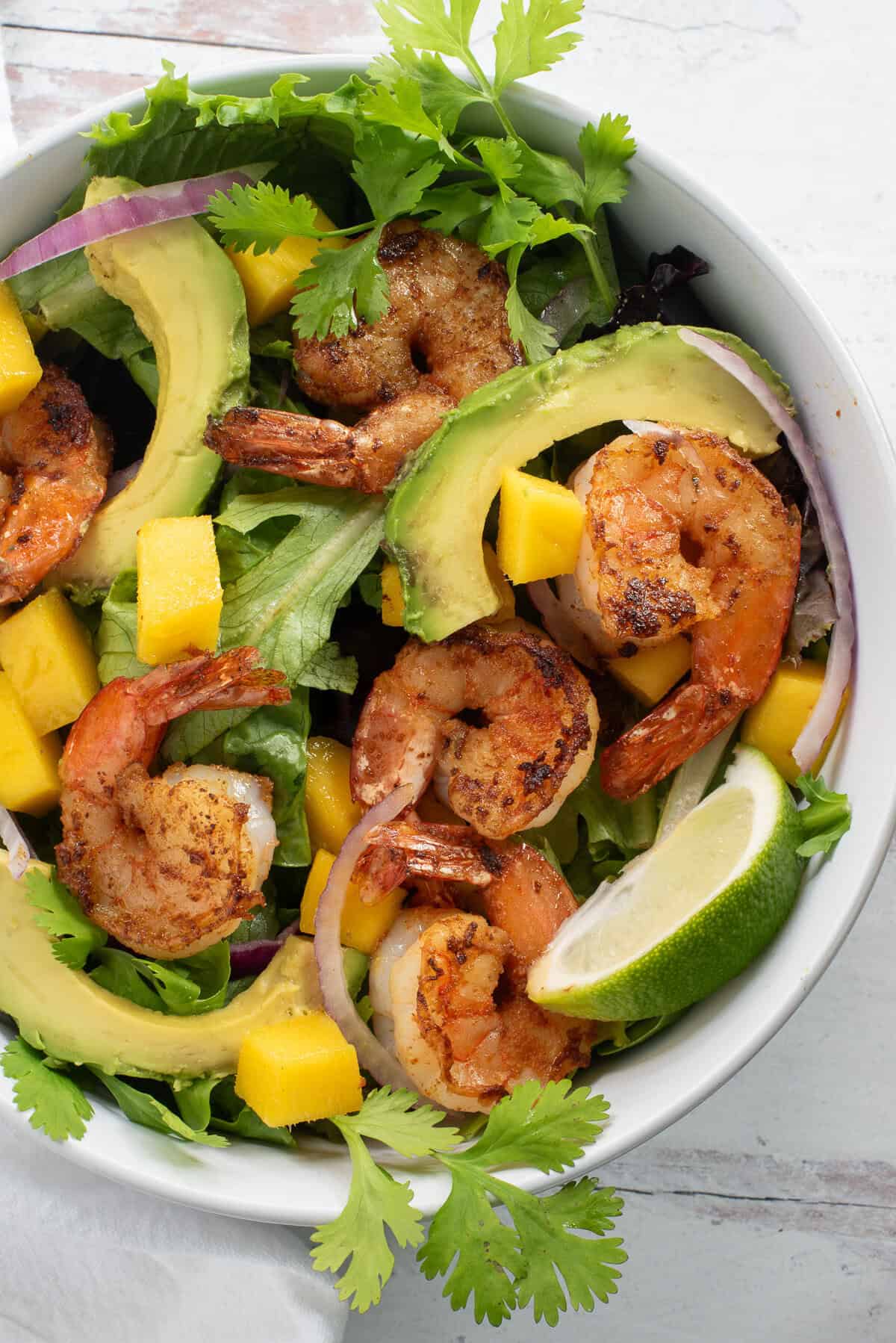 Avocado mango shrimp salad in a white bowl.