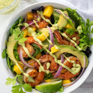 Mango Shrimp Salad in a white bowl, topped with Avocado Lime Dressing.