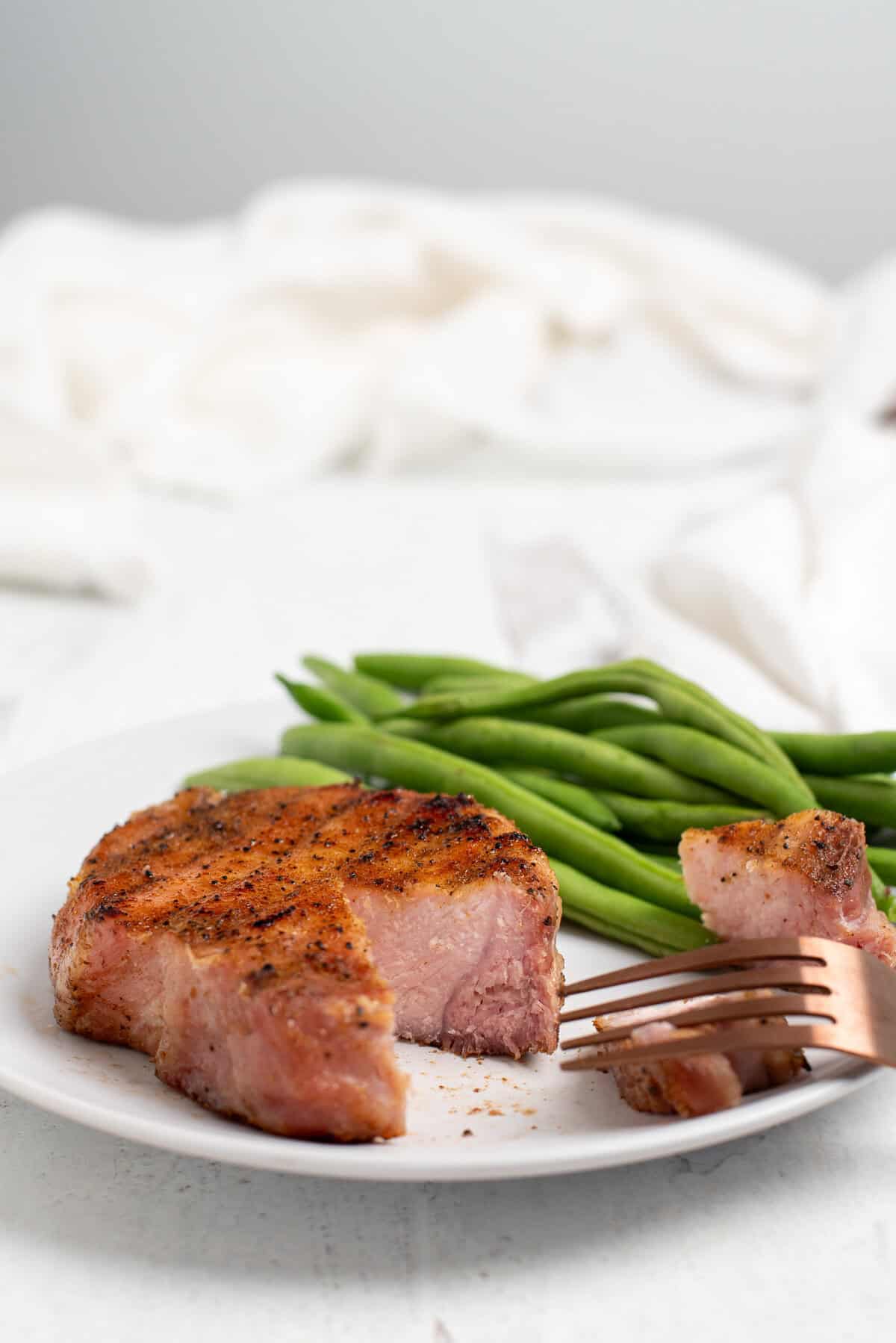smoked pork chop on plate with green beans.