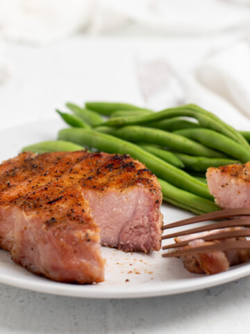 smoked pork chop on plate with green beans.