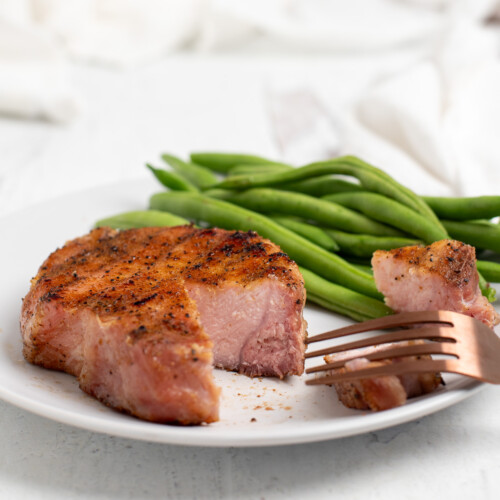 smoked pork chop on plate with green beans.