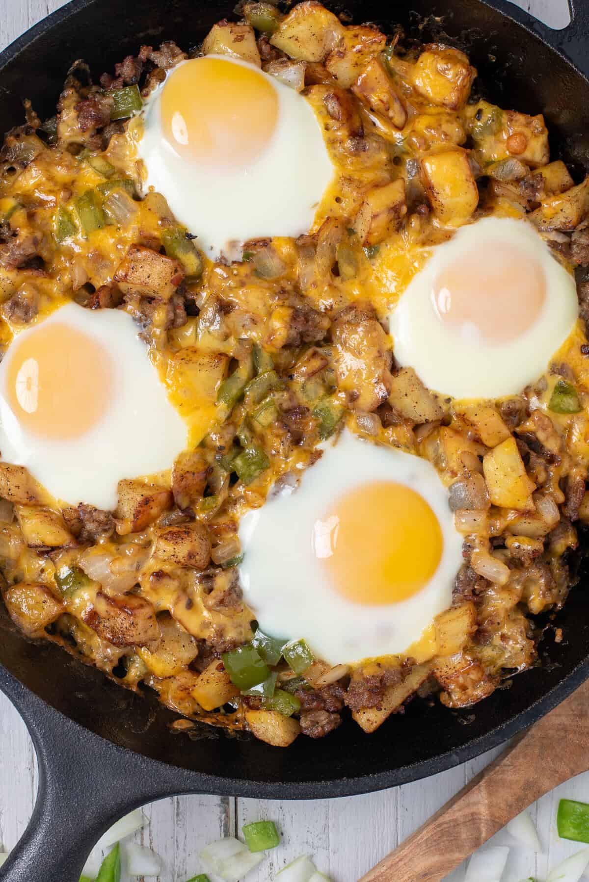 A breakfast skillet with sausage, topped with over easy eggs.