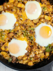 A breakfast skillet with sausage, topped with over easy eggs.