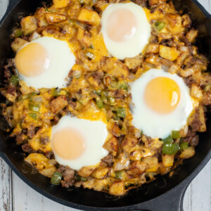 A breakfast skillet with sausage, topped with over easy eggs.