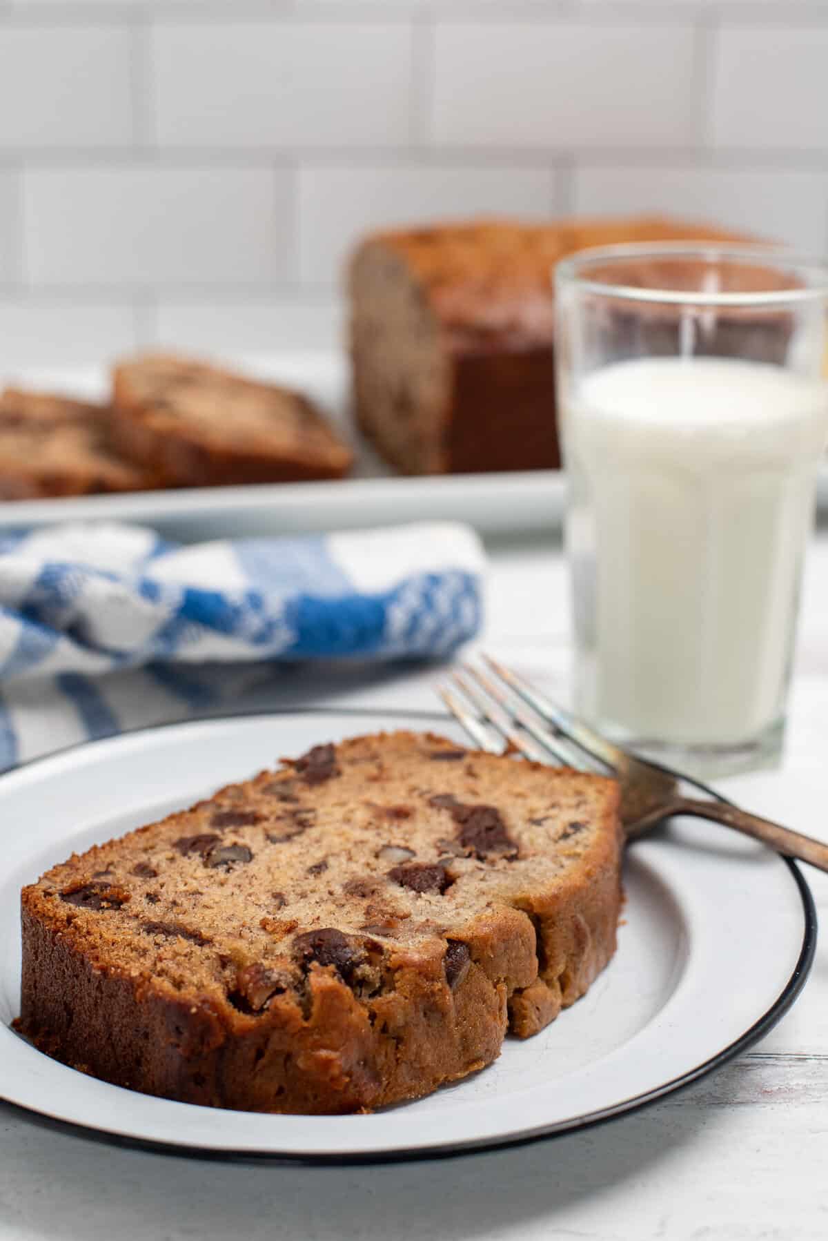 slice of banana nut bread on plate with milk. 