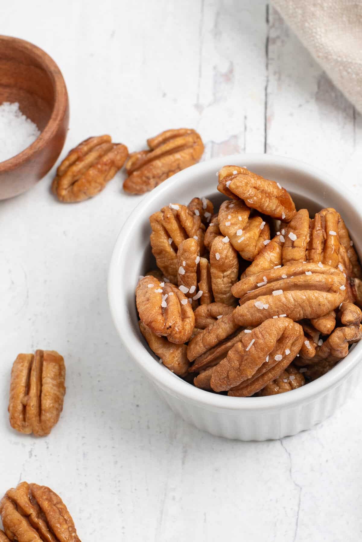 honey roasted pecans in bowl with salt behind.